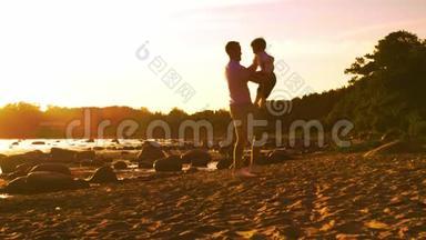 父亲在海边和儿子玩耍。 日落或日出的<strong>暖色</strong>。 有爱心的父母和美丽的孩子.. 爱情